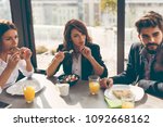 Group of business people having breakfast in company's restaurant. Focus on the woman in the middle
