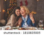 Family having Christmas dinner at home, gathered around the table, enjoying their time together; daughter hugging her mother and smiling