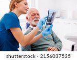 Small photo of Dentist explaining necessary procedures to patient sitting in dental chair while looking at jaw x-ray at stomatology clinic