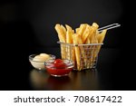 French fries in basket with ketchup and sauce isolated on black background. Front view.