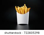 French fries in a white paper box isolated on black background. Front view.