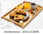 Breakfast in a tray filled with black Coffee, Cheese and chocolate croissant with orange juice with few strawberries