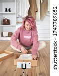 Small photo of Happy hipster gen z teen girl fashion social media channel blogger pink hair wear hoodie record unboxing vlog on phone video camera tutorial sit on floor open online store clothes order box, vertical.