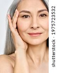 Small photo of Vertical portrait of middle aged Asian woman's face with perfect skin. Older mature lady touching pampering face with hand. Advertising of cosmetology salon rejuvenating spa procedures skincare.