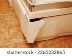 Small photo of Broken outer plastic corner of the shower tray. damage to the outer plastic frame of the pallet. A consequence of physical impact, impact or aging of the material.