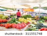Farmers' food market stall with variety of organic vegetable. Vendor serving and chating with customers.