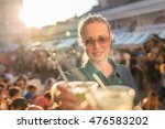 Beautiful young girl toasting outdoors on Open kitchen street food festival in Ljubljana, Slovenia. Popular summer urban tourist event in capital.
