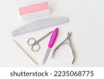 Small photo of Professional manicure set on a white table. Selective focus, noise. The concept of hand care, salon procedures. File, scissors, buff, bamboo stick, cuticle nippers