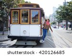 Young cheerful tourist taking a ride in famous cable car in San Francisco, California, USA