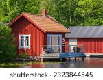 Picturesque red cottage by a lake with a jetty