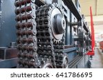 Triple strand roller chain going around three sprockets on industrial machine. Production, industry conceptual background.