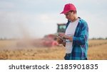 Small photo of Agriculture. Portrait of a farmer working on a digital tablet in a field in the background a tractor plows the ground in a field of wheat. farming agriculture concept. farmer business in the field