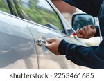 Small photo of Car thief with mask steal robber trying to open car door by screwdriver . Thieves try to breaking window car door at danger car parking vandalism looting.