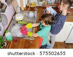Two young caucasian children are doing the dishes in kitchen at home