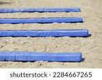Small photo of Show jumping poles obstacles, barriers, waiting for riders on show jumping training. Horse obstacle course outdoors summertime. Poles in the sand at equestrian center outdoors