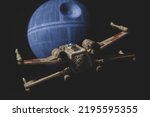 Small photo of AUG 28 2022: recreation of a scene from Star Wars A New Hope with a Rebel X Wing fighter approaching the Death Star - Disney Micro Galaxy Squadron vehicle