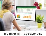 Woman working with data and graphs in spreadsheet document on desktop computer