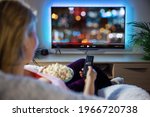 Woman relaxing at home in evening and watching TV