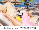 Woman holding e-reader device and reading e-book on the beach