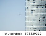 Abstract view of modern facade of skyscraper with closed and opened windows on clear blue sky background. A plane flies right in to the building, looks like it's going to crash in high-rise building 