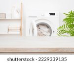 Empty wooden table in blurred laundry room with washing machine