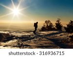 Backcountry skier reaching the summit at sunset