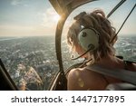 Portrait of beautiful blonde women enjoying helicopter flight. She is amazed by cityscape and wearing pilot headphones.
