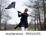 A young woman is fighting against the storm with her umbrella