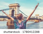 Thankful young redhead woman arms raised at Chain Bridge, Budapest, Hungary