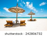 beautiful tropical beach with green coconut palms straw sunshades and wooden sunbeds in front of a turquoise sea with a blue sky, Mauritius, Africa 