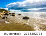 Small photo of Moeraki Boulders is the group of large spherical boulders. The South Island of New Zealand. Popular tourist attraction. Low tide in the Pacific ocean. The concept of exotic and ecological tourism