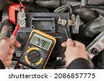 Car starter battery voltage measured with multimeter in a repair garage, bettry dead, time to replace