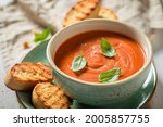 Delicious tomato soup made of tasty tomatoes. Soup with parmesan Red tomato soup in blue pottery.