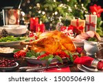 Christmas turkey dinner. Baked turkey garnished with red berries and sage leaves in front of Christmas tree and burning candles