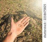 Small photo of an antique gold ring in the hand of a searcher, found on an old tract with the help of a metal detector, the foreground and background are blurred with a bokeh effect