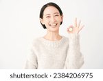 Small photo of Asian middle aged woman OK gesture in white background