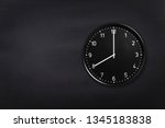Small photo of Black wall clock showing eight o'clock on black chalkboard background. Office clock showing 8am or 8pm on black texture