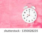 Small photo of Old fashioned alarm clock with twin bells and ringer showing 8 eight o'clock on pink texture as background