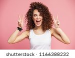 Image of happy young woman standing isolated over pink background showing peace gesture. Looking camera.