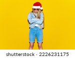 Disappointed Christmas woman in Santa Claus hat on yellow isolated background. Upset female complaining and arguing, talking troubled uneasy
