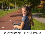 Happy child rides a bike on bike path. Cyclist child or teenager girl enjoys good weather and cycling. Environmentally friendly transport concept. Girl is smiling and laughs. Netherlands, Holland.