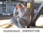 Small photo of Despair healthcare worker in white covid protective overalls.Tired Male caucasian doctor grabs his head cower in depression during coronavirus pandemic Paramedic overworked cry covered face with hands