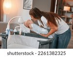 Small photo of Beautiful woman is holding hew newborn baby in hands indoors.