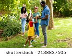 Happy african american siblings wearing bunny ears with family in backyard on easter day. unaltered, lifestyle, easter day, celebration, childhood, cultures and holiday concept.
