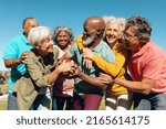 Small photo of Multiracial senior friends striving to get rugby ball against clear sky in yard at nursing home. Playful, summer, unaltered, sport, togetherness, enjoyment, support, assisted living and retirement.