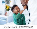 Laughing african american boy patient taking male doctor's stethoscope in hospital. Hospital, medical and healthcare services.