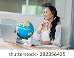Small photo of Pretty travel agent speaking to customer in the office