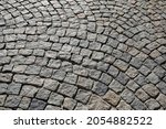 Many small stone blocks stacked side by side make up the surface of a paved road or sidewalk.