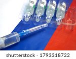 Small photo of syringe with a vaccine is held by hand in a glove on background of the Russian Federation flag, vaccine against coronavirus, Operation Warp Speed
