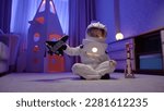 Small photo of Boy dreams of becoming an astronaut and flying into space. Dream is to fly in space. Small child in an astronaut spacesuit plays at home with toy Space Shuttle orbiter.